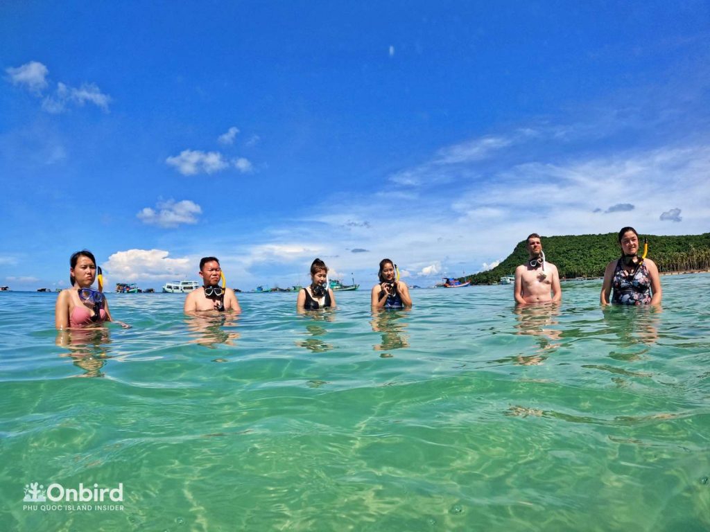 6 guests standing around the guide to listen to safety guides and snorkeling skill revives