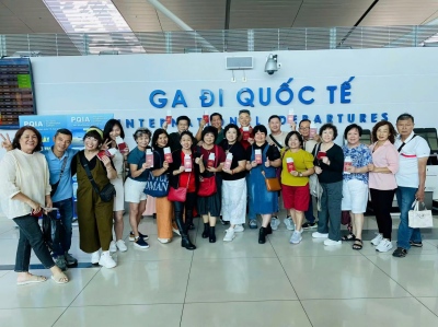 A large group of international travelers posing at the International Departure Terminal, preparing for their trip to Phu Quoc.