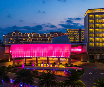 The dazzling facade of Corona Casino Phu Quoc at night, featuring prominent pink lights and modern architecture, inviting tourists for entertainment.