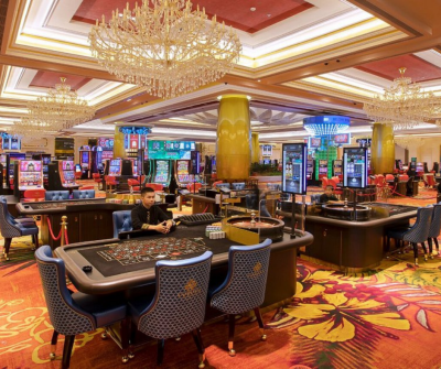 Interior view of Corona Casino Phu Quoc with gaming tables, slot machines, and luxurious chandeliers, creating a vibrant entertainment atmosphere.